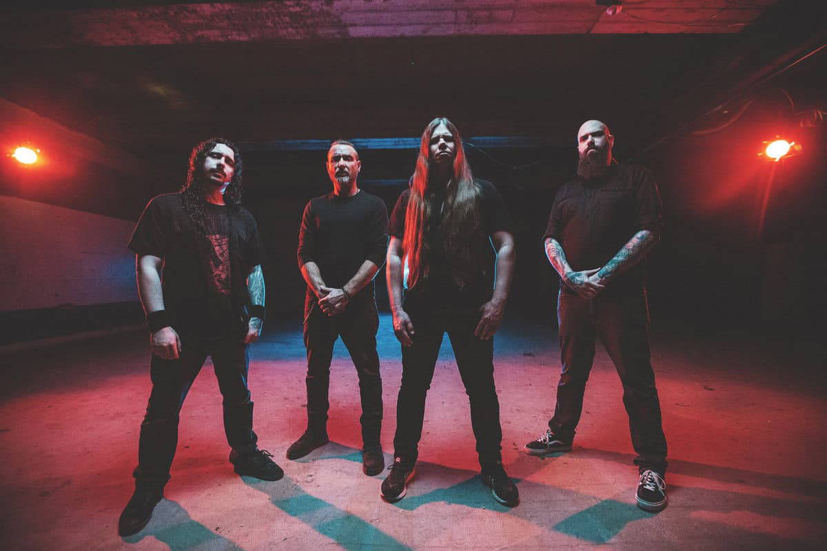 Aggressive metal band under red stage lighting, performing in underground concert venue.