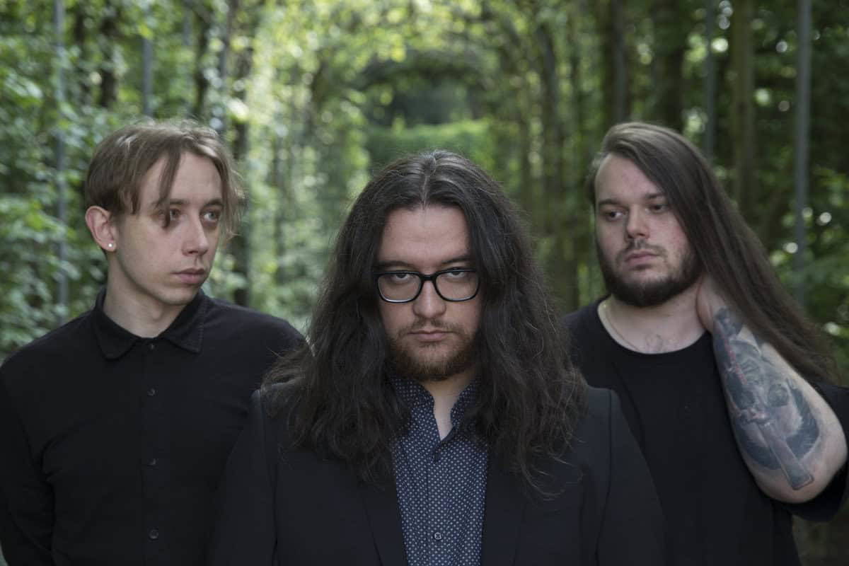 Dark-haired band members in a forest setting for MetalWar.gr.