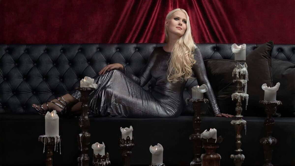 Zoe Marie Federoff in black leather dress with candles, dark velvet background, elegant and mysterious atmosphere.
