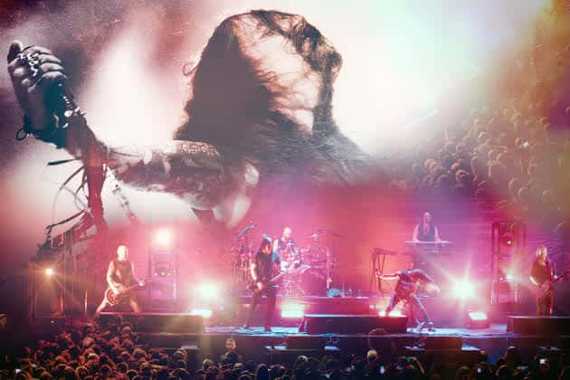 Live rock concert on a large stage with a band performing, colorful lights, and a cheering crowd in front of the stage.