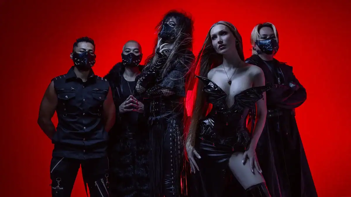Five performers in black outfits wearing masks pose together against a solid red background, giving a promotional group shot.