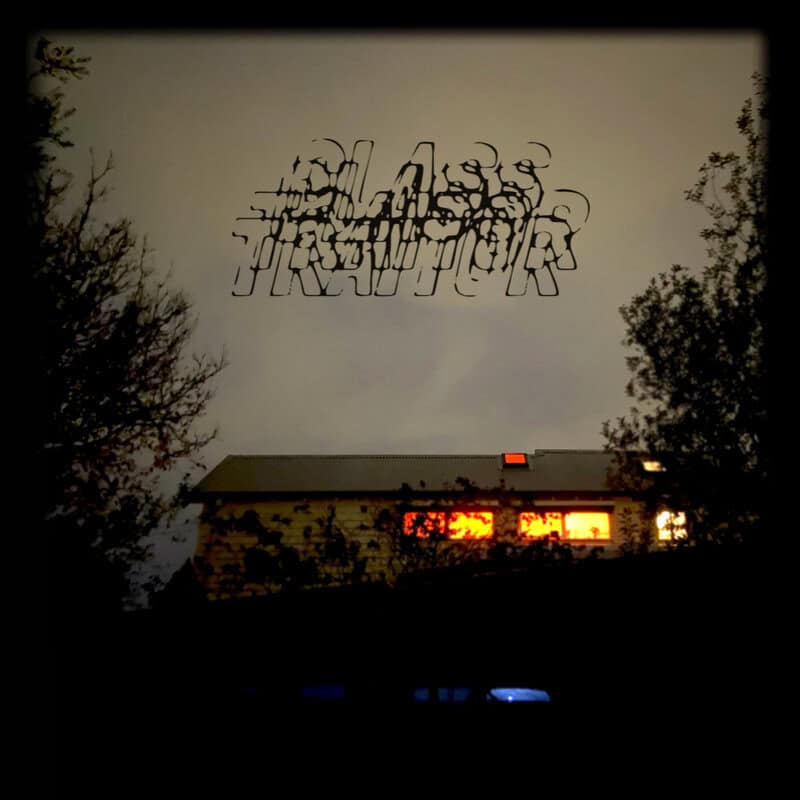 House at dusk with orange-lit windows, framed by trees; above it, a black, distorted graffiti-style wordmark in the cloudy sky—a surreal urban scene.