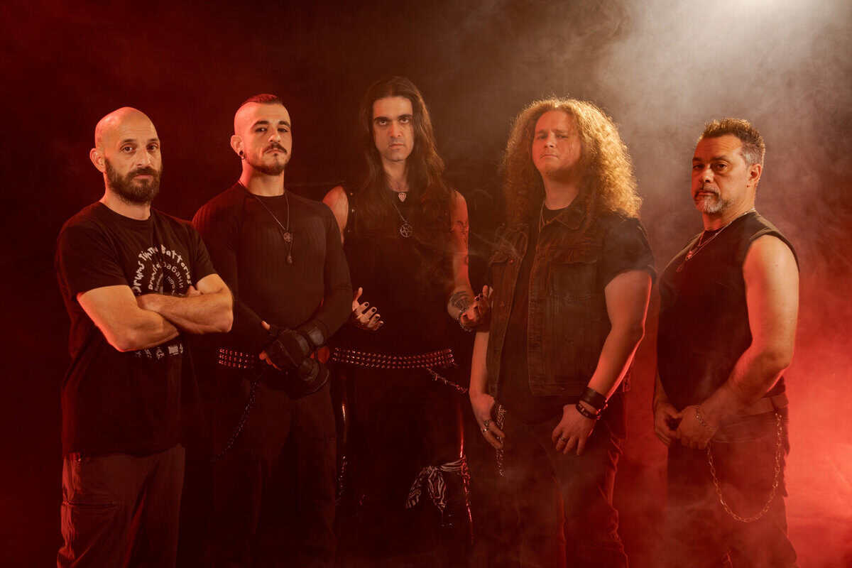 Five male musicians in black outfits stand in a red-lit, smoky studio, looking serious for a band promo photo.