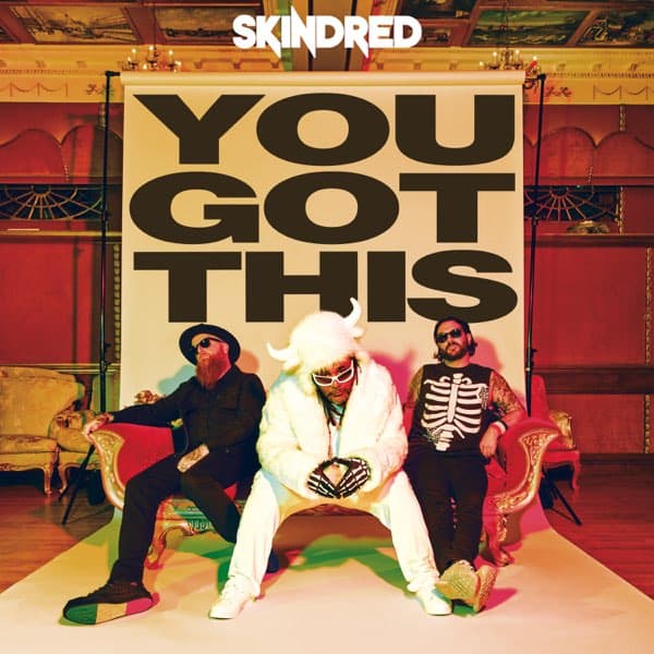 Three people sit on a stage in front of a large poster that reads 'YOU GOT THIS,' with the Skindred logo above them.