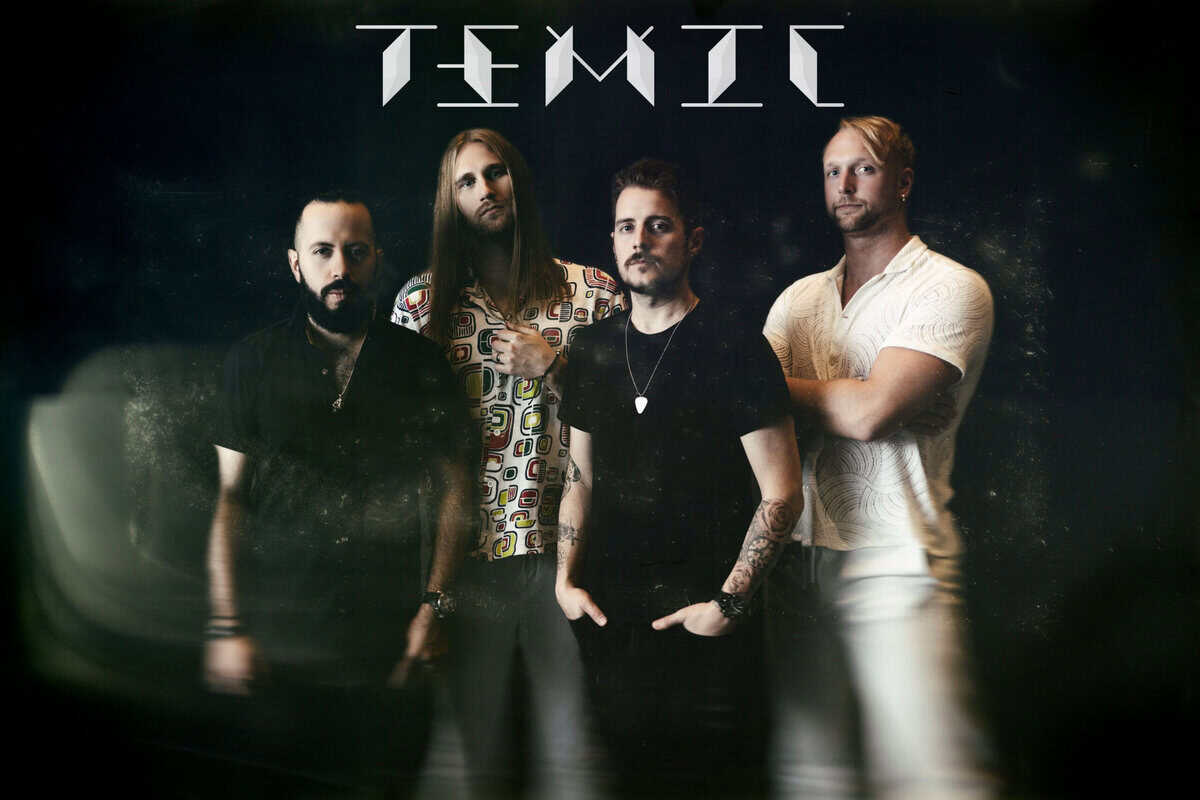 Four-member rock band posing in a studio against a dark backdrop; one wears a patterned shirt, others in black or white shirts, with a stylized logo above them.