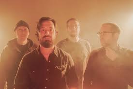 Four men posing as a rock band in a warm, hazy backlit photo for a promotional shot