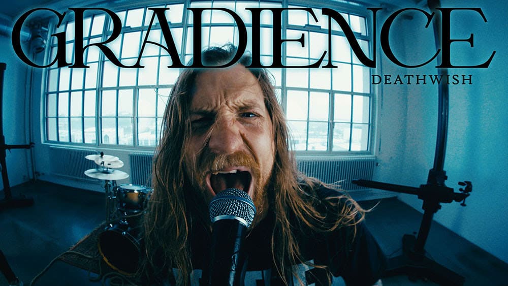 Close-up of a long-haired singer shouting into a microphone in a bright rehearsal studio, drums visible in the background; large band name text above.