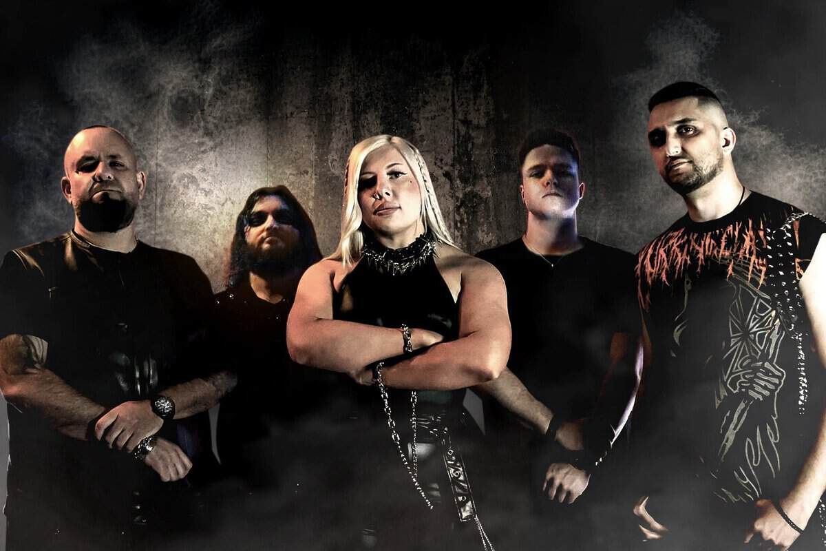 Five-member metal band posing in a smoky backdrop, woman in the center with arms crossed surrounded by four men.