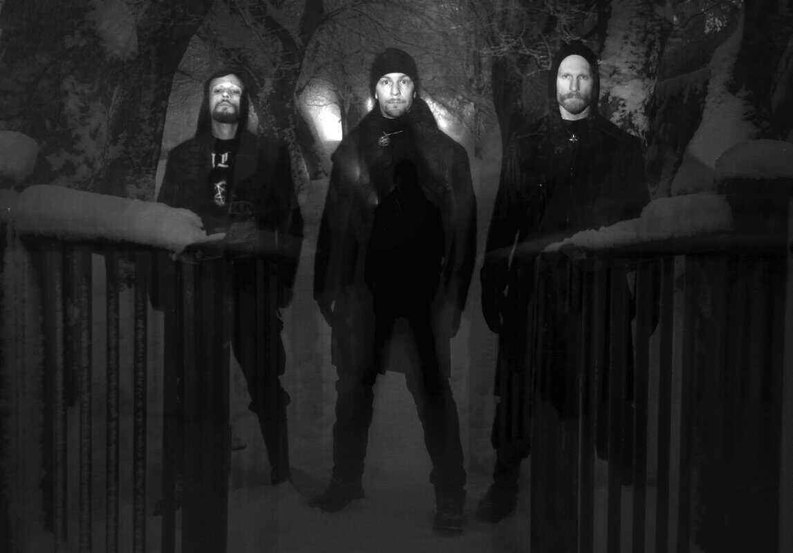 Three men in dark hoodies standing in a snowy forest at night, with a double-exposure effect creating ghostly silhouettes.