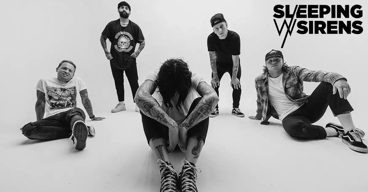 Black-and-white group photo of the band Sleeping With Sirens in a studio, five members posed around the center singer with tattoos; logo in top-right.